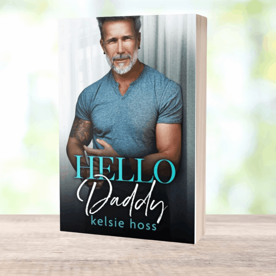 a paperback copy of Hello Daddy by Kelsie Hoss, featuring an attractive older man on the cover 
