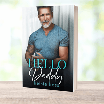 a paperback copy of Hello Daddy by Kelsie Hoss, featuring an attractive older man on the cover 