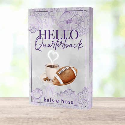 a paperback copy of Hello Quarterback by Kelsie Hoss, the cover features a football and a cup of cocoa 