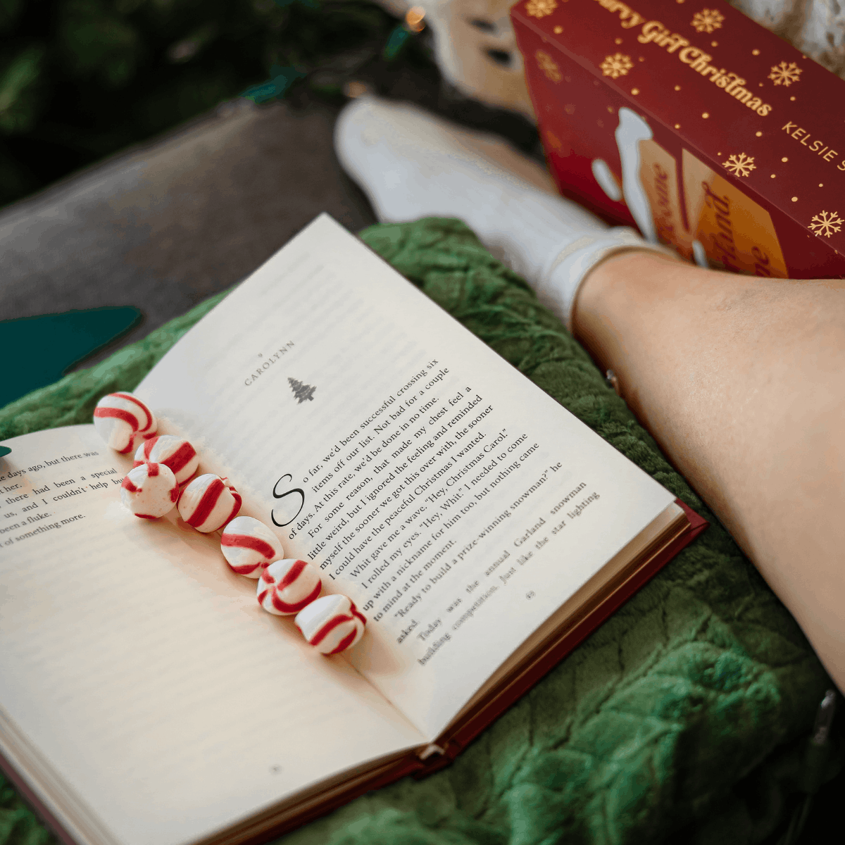 a curvy girl christmas box set next to an open book with christmas mints along its pages 