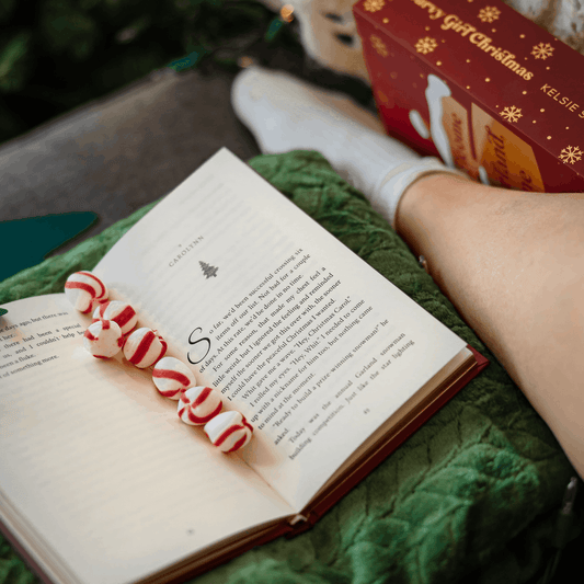 a curvy girl christmas box set next to an open book with christmas mints along its pages 