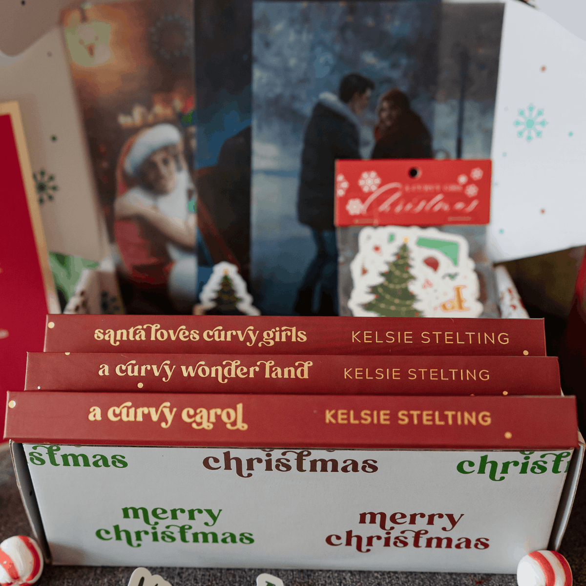 3 books, Santa Loves Curvy Girls, a Curvy Wonderland, and a Curvy Carol. All written by Kelsie hoss and displayed on a christmas gift themed background