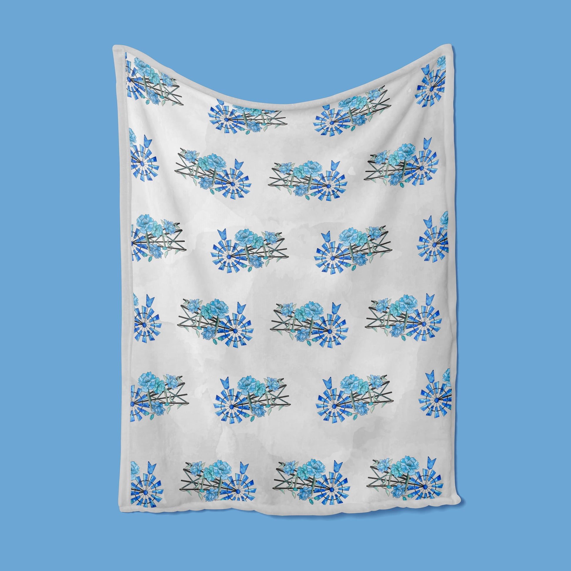 A white blanket with blue floral patterns is hung on a blue background
