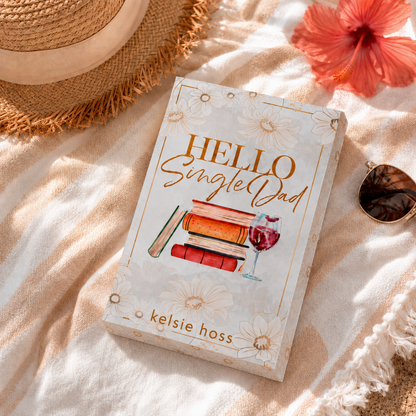 Book titled 'Hello Single Dad' by Kelsie Hoss on a textured surface with a hat and flower.