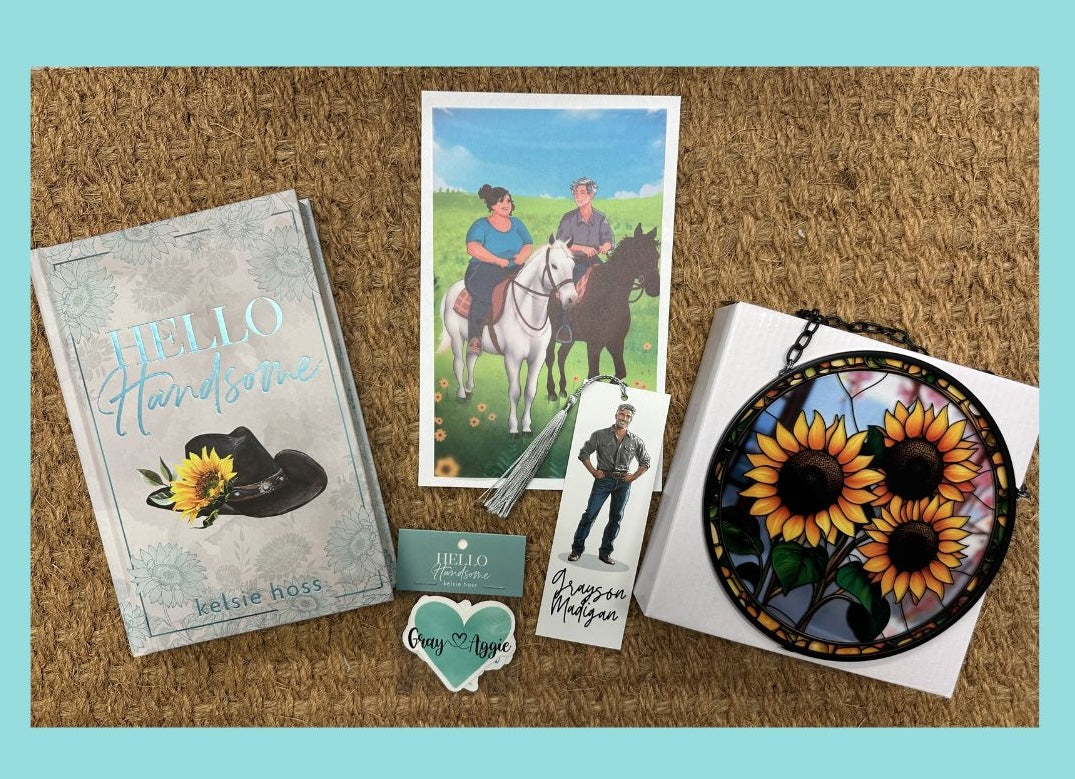 A rustic background with a light blue background displays several items. A book to the left titled Hello Handsome by Kelsie Hoss, it's cover decorated with a cowboy hat adorned with a sunflower. To its right is a heart sticker, an artistic representation of a photo of two characters, a tassel book mark and a piece of jewelry with a sunflower design