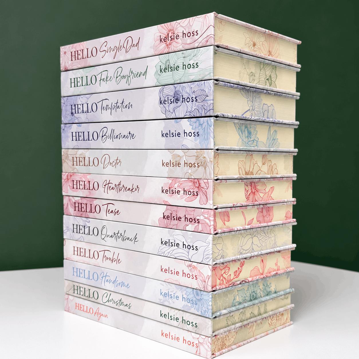 A stack of special edition hardcover copies of The Hello Series by Kelsie Hoss, with light covers and sprayed floral designed edges